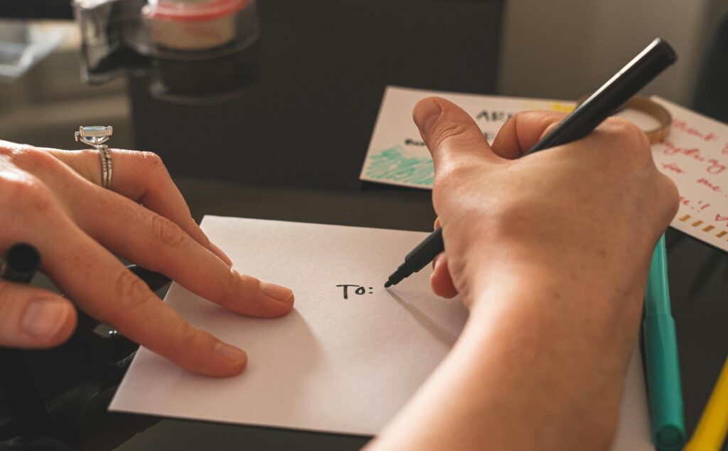pexels photo 3951845 3951845 Hands writing on an envelope with marker, emphasizing handwritten correspondence.